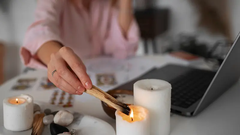 Psychic Medium Reading woman lighting candles in front of her laptop